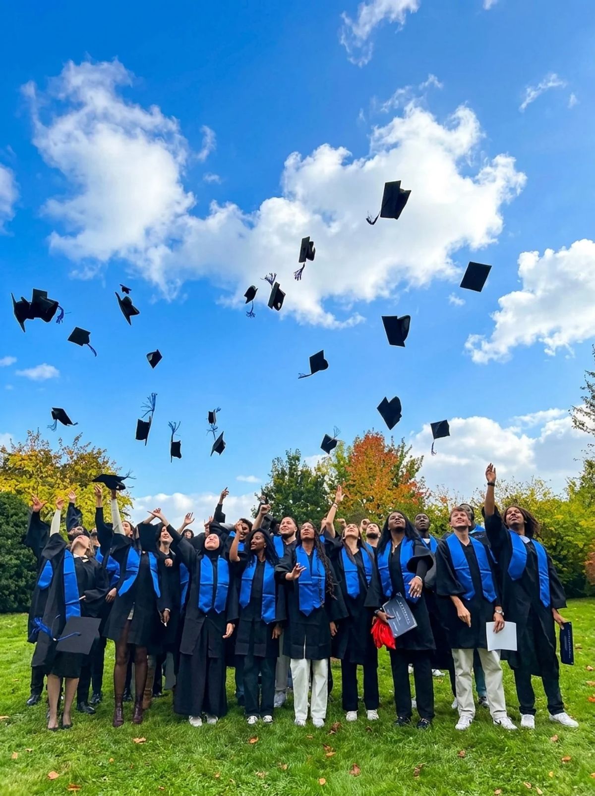 Diplômés de l'EMSCA lançant leurs chapeaux sous un ciel bleu lors de la cérémonie de remise des diplômes